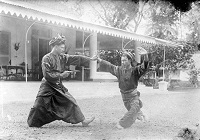 A black and white historical photograph of two men engaging in Pencak silat, West Sumatra.