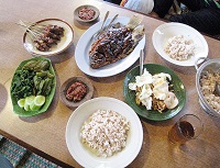 Typical traditional Sundanese cuisine, Red rice with satay, raw vegetables with sambal, Grilled Gourami, and raw vegetables in peanut sauce, and tea