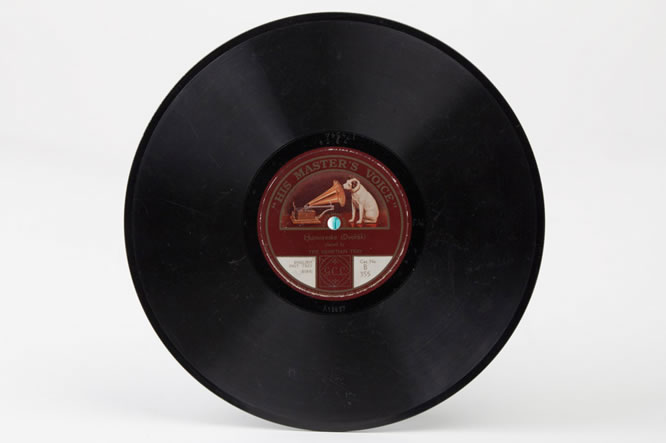 A large round black vinyl record with a dog and a gramophone printed on the maroon label at the centre.