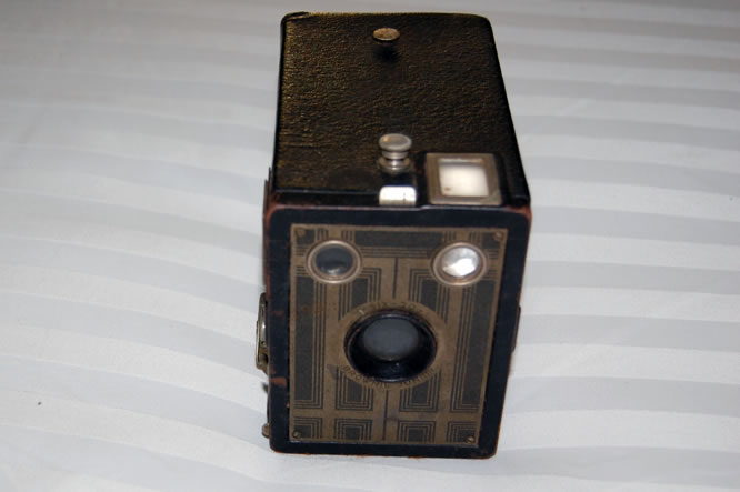 An old black box-shaped camera made from hard cardboard. It has three round windows at the front.