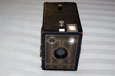An old black box-shaped camera made from hard cardboard; it has three round windows at the front.
