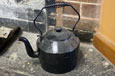 A black kettle with spout and handle.