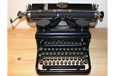 A black typewriter with five rows of black keys and a large space bar.