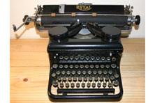 A black typewriter with five rows of black keys and a large space bar