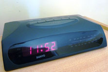A black digital clock with red numbers that read 11:52