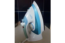 A blue and white electric steam iron that is sitting upright