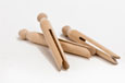 Three brown wooden dolly pegs with a knob at the top and a split down the middle