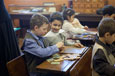 Children sitting at school desks working together to complete a jigsaw puzzle.