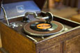 A wooden record player with an open lid and a record on the turntable.