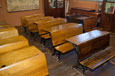 Rows of old wooden school chairs and desks with iron legs.