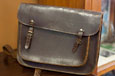 A brown satchel with two locking straps.
