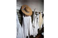 White smocks and a straw hat hanging on hooks in a school cloakroom.
