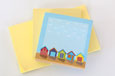 Three square sticky note pads; two yellow and one blue with a beach hut border