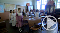 Students inside classroom standing to attention beside their desks