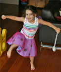 A girl dances in front of the camera, arms outstretched and legs swinging