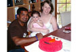 Mum and dad celebrating a toddler's birthday with an Elmo cake.