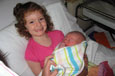 A young girl in a hospital bed holding a newborn baby.