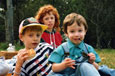 Three children in a park having a picnic.