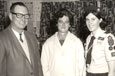 A teenager, dressed in her Girl Guide uniform, standing with her parents for a photograph.