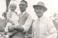 An elderly man and a younger man holding a toddler.