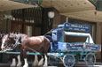 A blue and white carriage pulled by two draught horses.