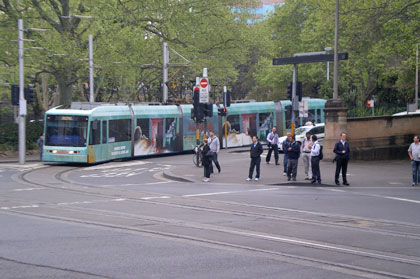 A green five car light rail rounding a corner on its tracks.