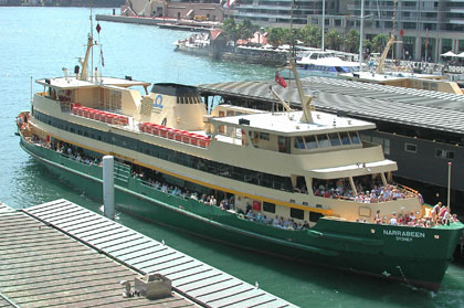 The Narrabeen, a ferry with a green hull and a cream body and many people on board at Circular Quay