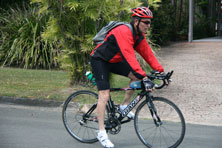 A man wearing a red helmet riding on a black bicycle