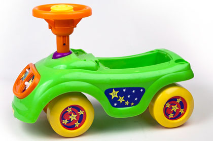 A shiny green plastic car with yellow wheels and an orange steering wheel decorated with smiley stars