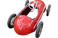 A red pedal car with four black wheels and a white steering wheel.