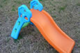 A green and blue plastic slippery dip with an orange slide.