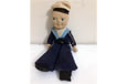 A sailor doll in a long blue coat standing on one leg.