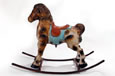 An old spotted rusty rocking horse made of metal with a blue blanket and a red saddle.