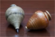 Two small wooden spinning tops—one white and one brown.