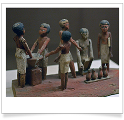 Small wooden figurines of people wearing loin cloths and around a vat and jars, making beer.