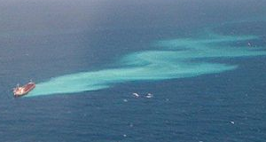 Oil spilling from a large ship into the water of the Great Barrier Reef.