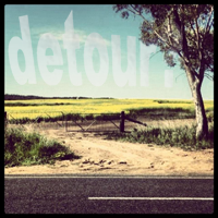 A bitumen road in the foreground with a dirt road leading to a gate. The text 'detour?' appears subtly in the sky.