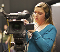 young woman wearing headphones using video camera