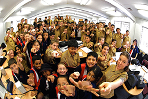 photo of students in class pointing and smiling to camera