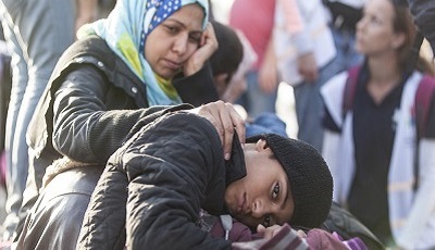 Photo of a Muslim woman looking sadly at her son who is hunched over and seems hopeless.