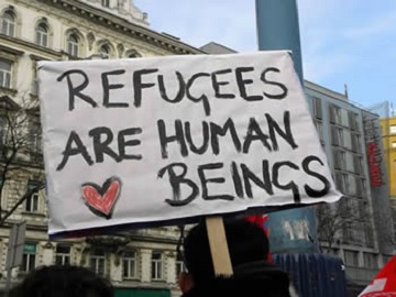 Protestors holding a sign that reads 'Refugees are human beings'.