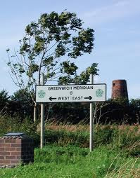Road sign showing Greenwich Meridian at zero with arrows pointing West and East.