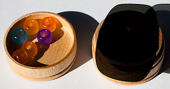 Two containers with beads, one covered with a sunglass lens.