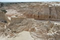 Creamy white soil makes up eroded gullies in a desert scene.