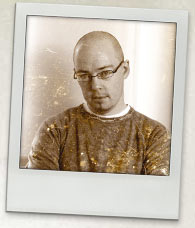 Photo of John Boyne. A young man with a bald head and wearing glasses.