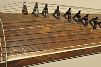 Koto thumbnail: section of a kimino showing the strings and bridges that hold the strings off the base board.