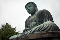 Buddhism thumbnail: a very large greenish stone statue of a man in robes sitting with his legs crossed