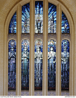 Arched stained-glass window with images of uniformed people in the five lower sections.