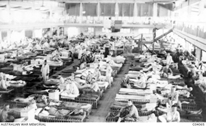 A large room with long rows of beds with men lying or sitting on them