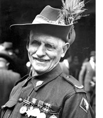 Elderly man in military uniform with medals and feather in his cap; he smiling at the camera